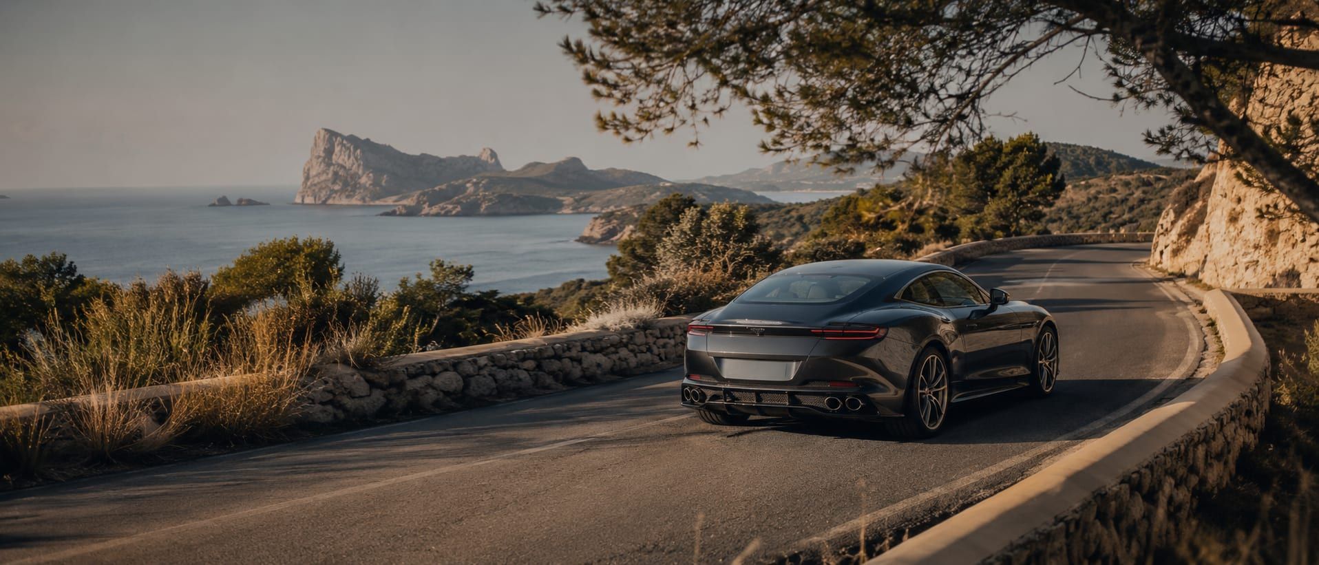 A coastal road winding along the Ibiza shoreline at golden hour.